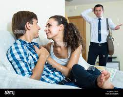 Shocked husband discovering his young cheating wife with lover on couch  Stock Photo - Alamy