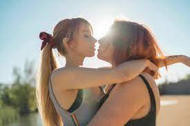 Lesbian couple doing romance while standing against sky stock photo