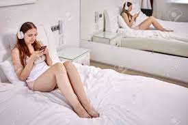 スマートフォンでベッドに座っている女性のためのビデオ通話。の写真素材・画像素材 Image 179377831