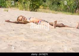 Teen girl sunbathes alone on a river sandy river beach Stock Photo - Alamy