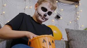 skeleton makeup holds a bucket of candy