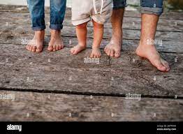 Mutter, Vater und Baby gehen nackte Füße auf die Holzbrücke. Fröhliche junge  Familie, die zusammen Zeit verbringt, draußen läuft, in der Natur, im  Urlaub, im Freien geht Stockfotografie - Alamy