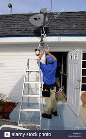 Adult Male Installer Attaches A Satellite Dish To A Roof
