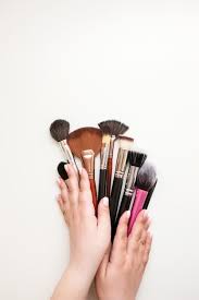 hands with variety of makeup brushes