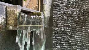 Water Falling Down From A Stone Wall In