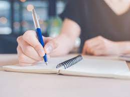 Woman hand is writing on a notebook with a pen. - Audienz