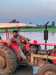 man driving a tractor on a paddy field