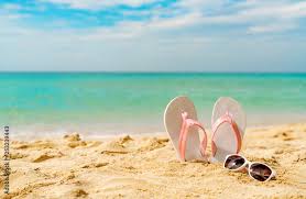 Pink and white sandals, sunglasses on sand beach at seaside. Casual fashion style flipflop and glasses. Summer vacation on tropical beach. Fun holiday travel on sandy beach. Summertime. Summer vibes. Stock Photo |