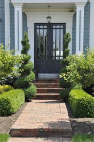 Ornate Shrubs And A Brick Walkway Make This Front Door
