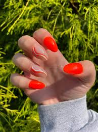 bright orange nails with white swirls