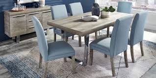 A small dining space with a wooden dining table paired with black chairs over concrete flooring. Cindy Crawford Home San Francisco Gray 5 Pc Dining Room With Blue Chairs Rooms To Go