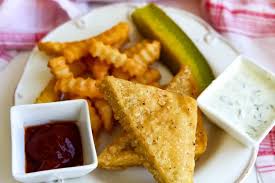vegan fish and chips with a pickle on the side along with ketchup and vegan tartar