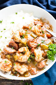 a bowl full of shrimp and sausage gumbo with a sprig of parsley