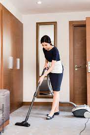 brunette housemaid cleaning carpet with