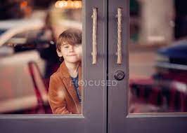 Boy Looking Through Glass Doors