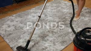 a woman vacuuming a grey rug the