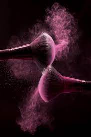 cosmetic brushes in pink mist of powder