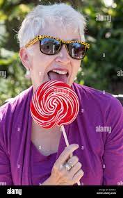Happy Mature Woman in Sunglasses Enjoying Licking Her Oversized Lollipop,  USA Stock Photo - Alamy