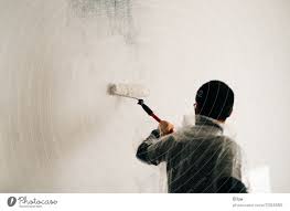 A Man Paints A Wall With A Paint Roller