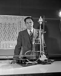 Glenn T Seaborg In Front Of A Periodic Chart Of The Atoms