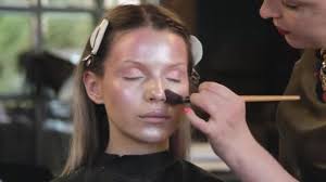makeup artist applies cosmetics to face