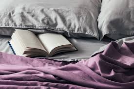 Open Book On Bed With Purple Bedspread