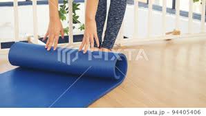 woman hands rolled up yoga mat on gym