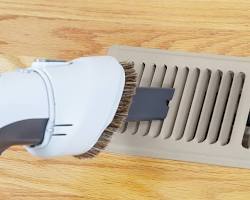 Image of someone vacuuming an air vent cover