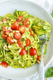 zucchini noodles with pesto in a bowl with tomato slices for lunch
