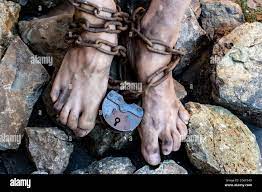 Les pieds sales de l'esclave sont enroulés dans une chaîne rouillée avec  une grande serrure. Concept de travail esclave Photo Stock - Alamy