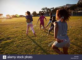 Elementary School Kids Playing Football In A Field Back