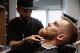 Focused Barber Shaving Beard Of Young Man by Milles Studio - Grooming, Shaving