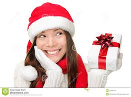 Santa girl holding christmas gift. Young happy woman in santa hat looking sideways showing Christmas present isolated on white background. - santa-girl-holding-christmas-gift-21395104