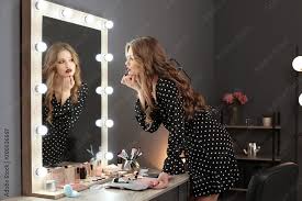 young woman applying makeup near mirror