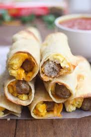 a stack of egg and sausage breakfast taquitos with salsa in the background