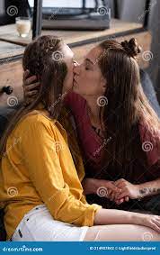 Two Lesbians Kissing and Holding Hands while Sitting on Sofa in Living  Room. Stock Photo - Image of gender, caucasian: 214907842