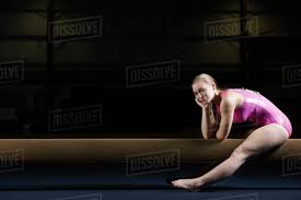 female gymnast sitting on balance beam