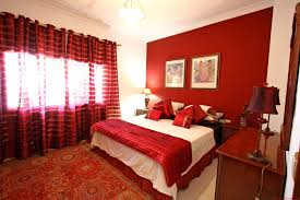 Pillows on the bed have the same pattern, and a red ottoman, curtains, floor lamp, and seating add more touches of color. 10 Red Bedroom Ideas 2021 Must Try For Brave Souls