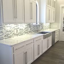 Grey cabinets and a white marble countertop look elegant alongside a green and metal mosaic backsplash for a modern space kitchens. White Cabinets With White Glass Backsplash Novocom Top