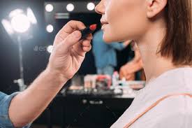 makeup artist holding red lipstick