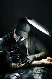tattoo artist in black gloves drawing