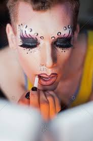 man applying drag queen cosmetics stock