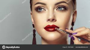 makeup artist applies red lipstick