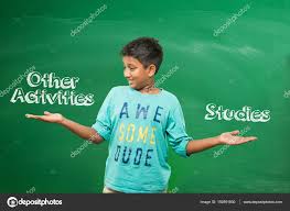 Indian School Kid Or Boy Standing In Front Of Green Chalkboard With