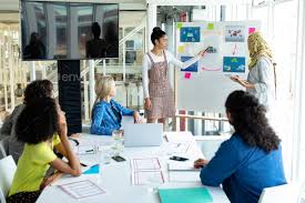 Mixed Race Businesswoman Giving Presentation On Flip Chart During Meeting