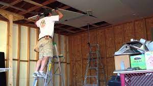 one man drywall installation on ceiling