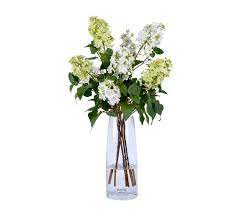 faux white lilacs in tall glass vase