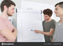 Male Students Looking At Graph On Flip Chart Stock Photo