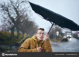 man holding broken umbrella strong wind