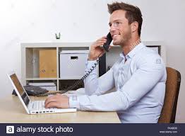 Happy Business Man With Laptop Computer In Office Making Phone Calls
